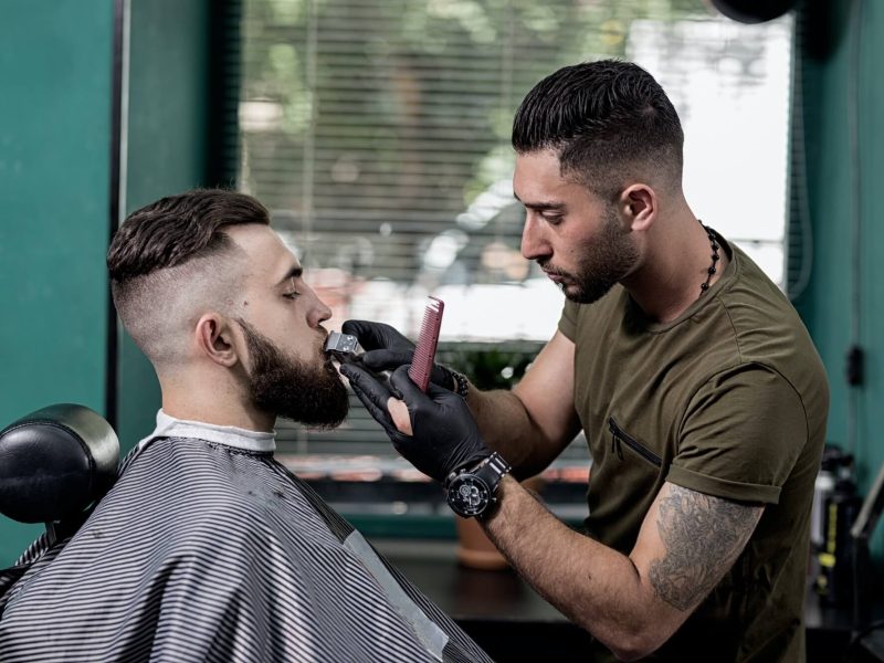 barber-trims-mustache-of-dark-haired-stylish-man-at-a-barbershop.jpg